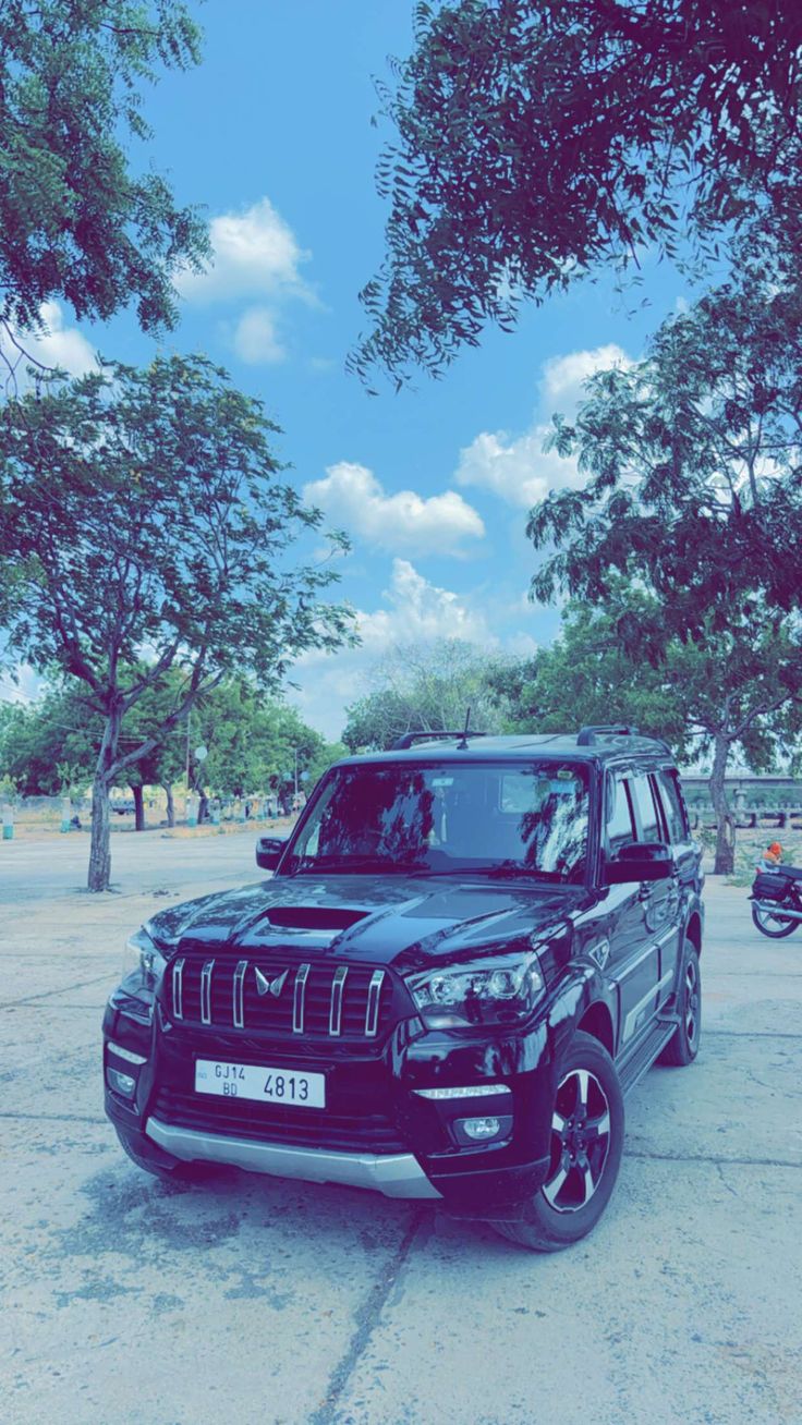 a black suv parked in front of some trees