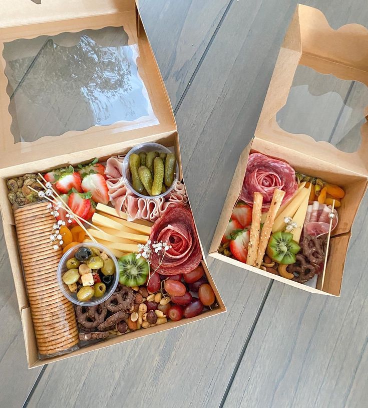 two open boxes filled with different types of food on top of a wooden table next to each other