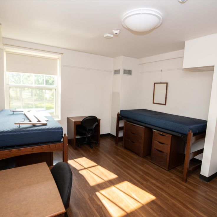 a room with two beds and a desk in it