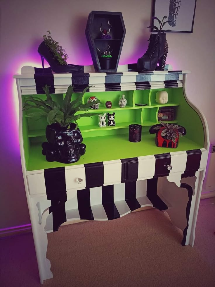 a green and white desk with black and white stripes on the bottom shelf, potted plants in front of it