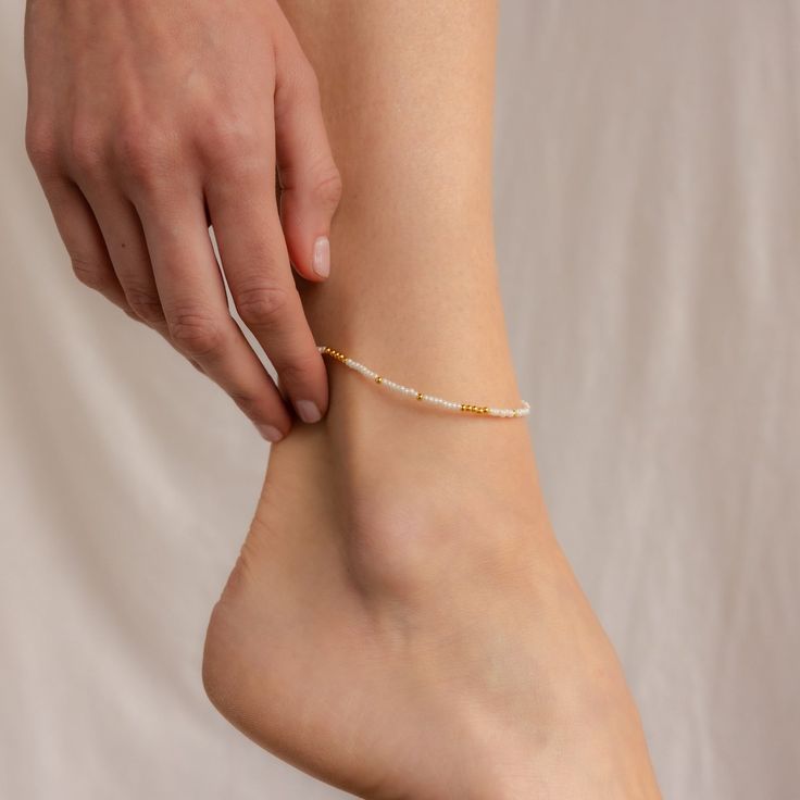 Get ready to dance with joy wearing our Dainty Pearl Beaded Anklet. This playful accessory, embellished with tiny pearls, brings a sprinkle of magic and whimsy to your summer adventures. Whether you’re wandering along sandy shores or twirling in a boho garden, this anklet adds a touch of fairy-tale charm to your ensemble. Material: High Quality Solid 925 Sterling Silver Finish: Sterling Silver ∙ 18K Gold Featuring ~2mm White & Gold or White & Silver Beads across the anklet. Anklet length is adju Adjustable White Anklets For Spring, Adjustable Pearl Anklets For Summer, Adjustable Gold Beads Anklets, Summer Pearl Anklets As Gift, Summer White Pearl Anklets, Adjustable Beaded Pearl Anklets, Adjustable White Pearl Anklets, White Pearl Anklets For Summer, Delicate White Adjustable Anklets