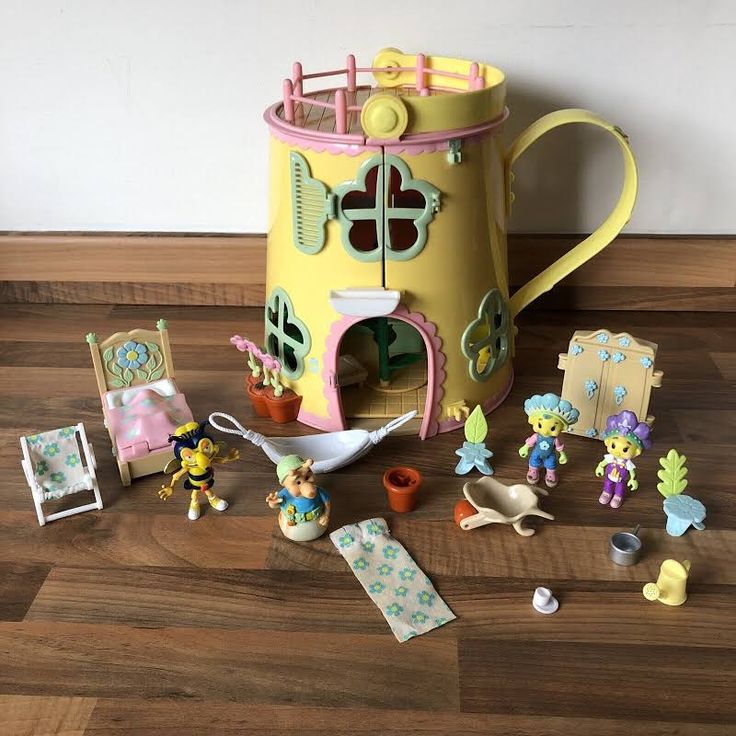 a yellow toy house with figurines and toys around it on a wooden floor