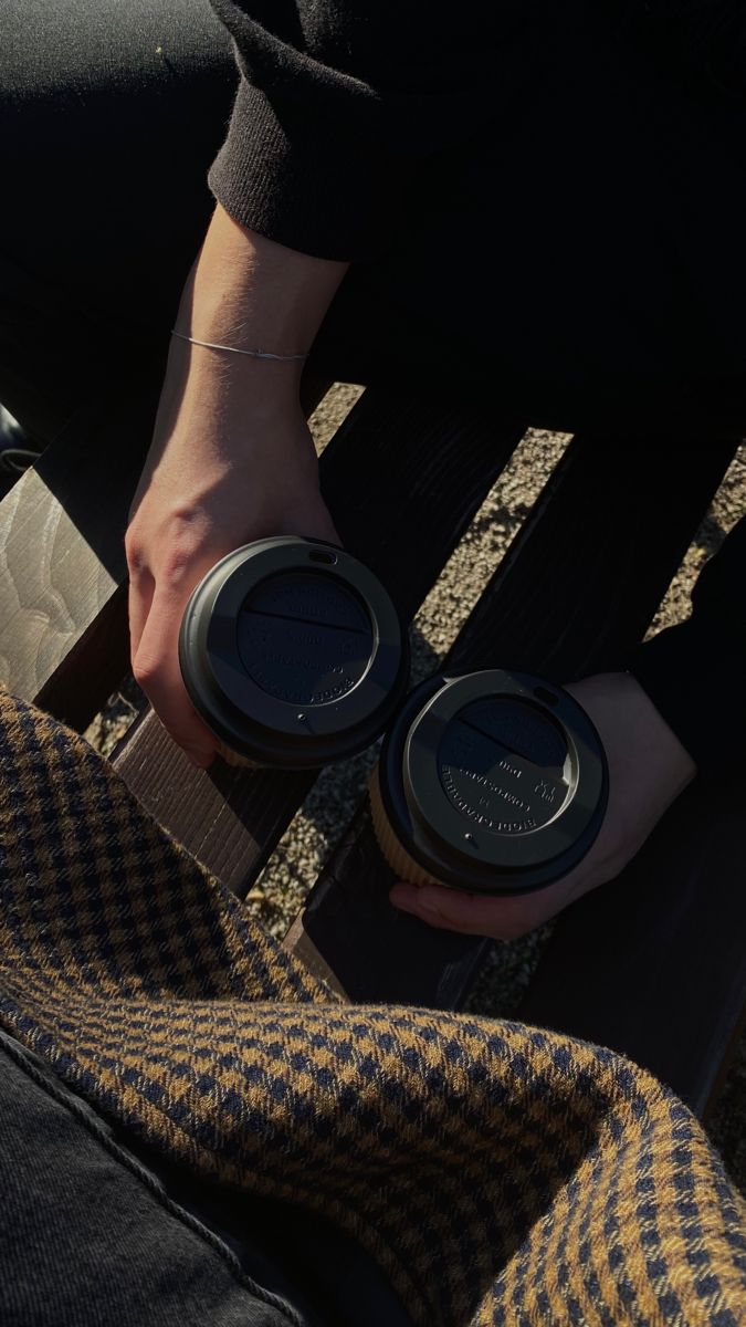 the person is holding two coffee cups in their hands