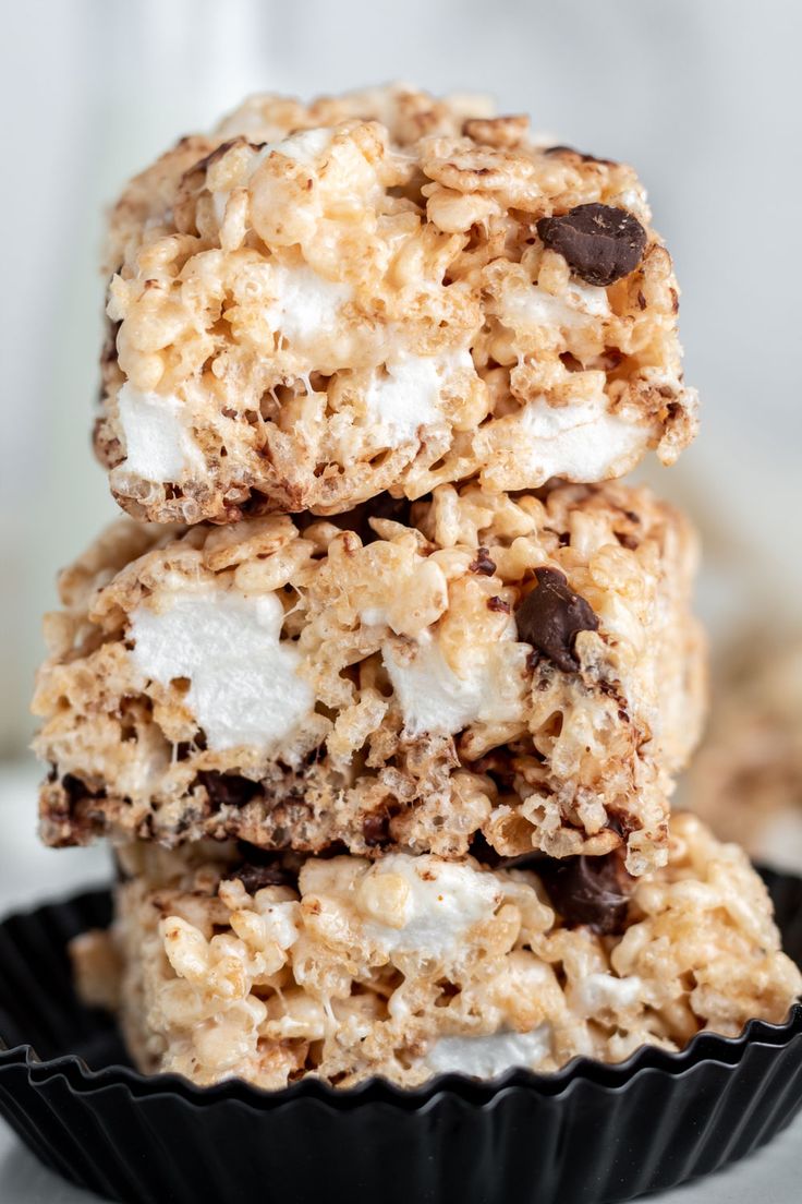 three cookies and marshmallows are stacked on top of each other in a black bowl