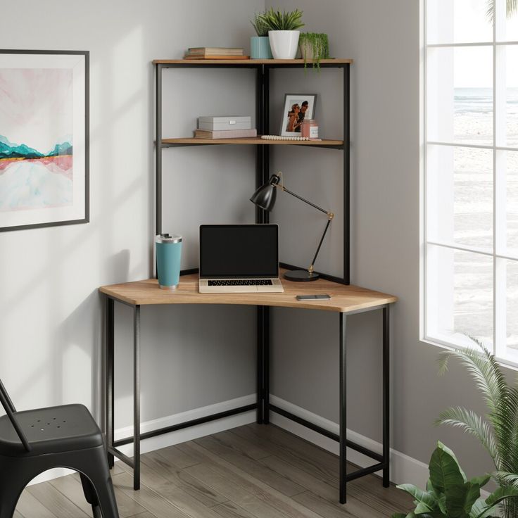 a corner desk with a laptop on it in front of a window and potted plant