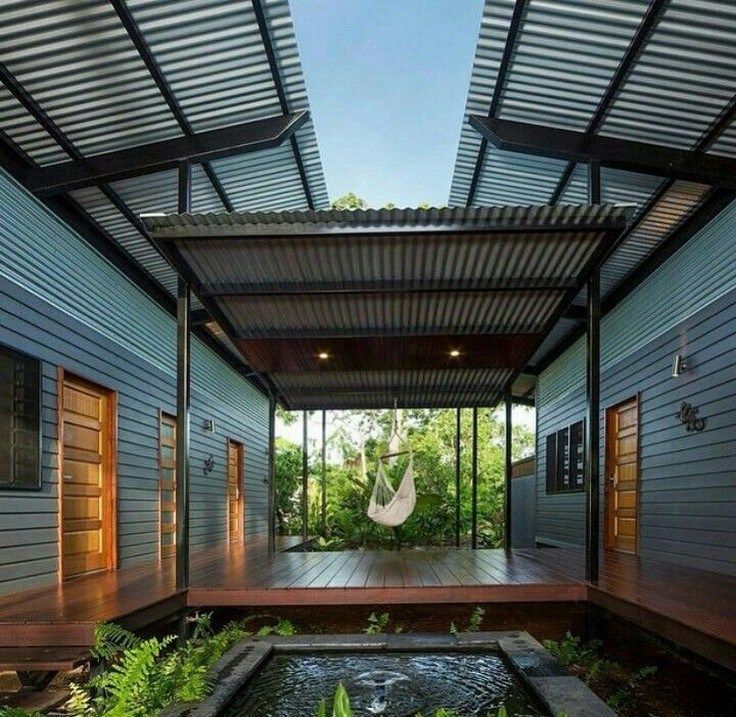 an outdoor room with a hammock and water feature in the center, surrounded by greenery