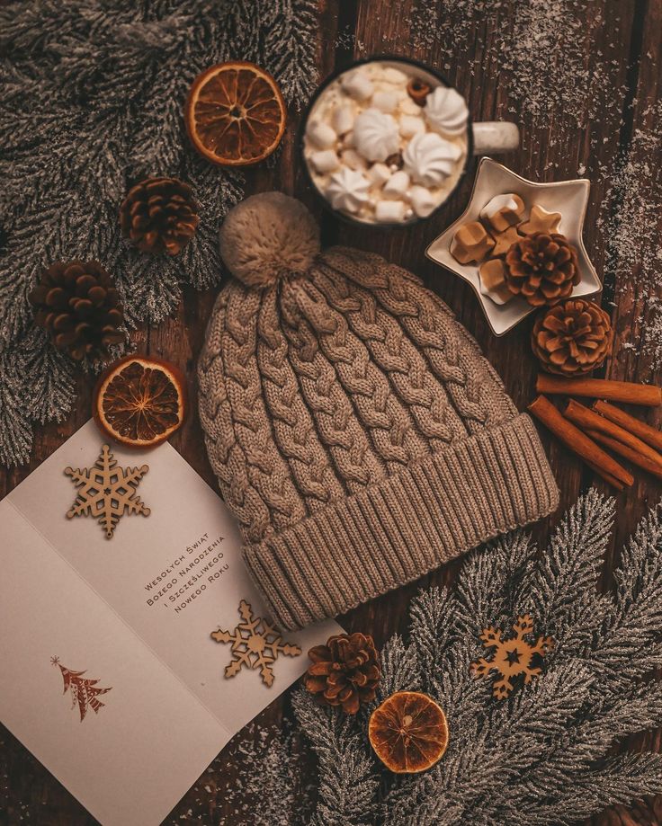 an open book, orange slices and cinnamons on a wooden table next to christmas decorations