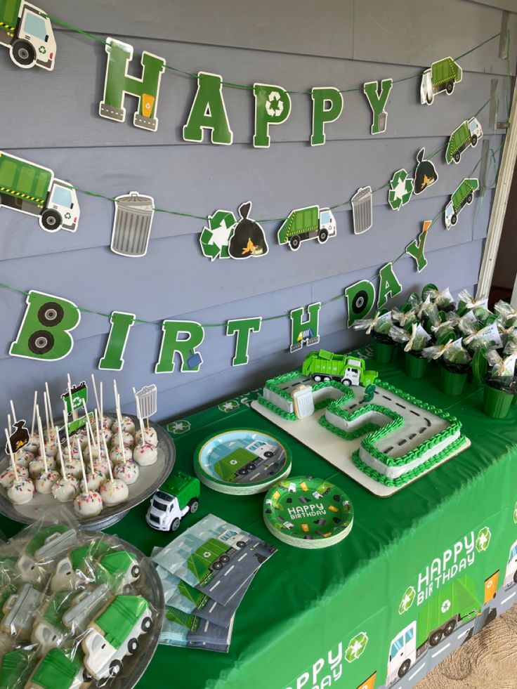 a green table topped with cake and cupcakes next to a sign that says happy birthday