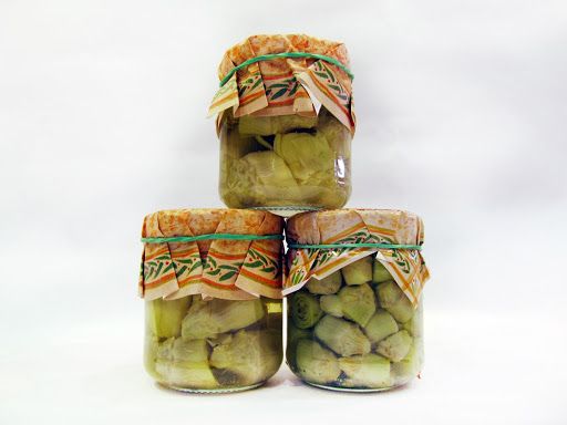 four jars filled with pickles sitting on top of each other