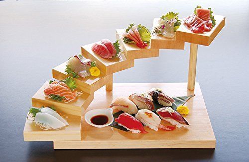 sushi is arranged on a wooden stand with sauces and garnishes