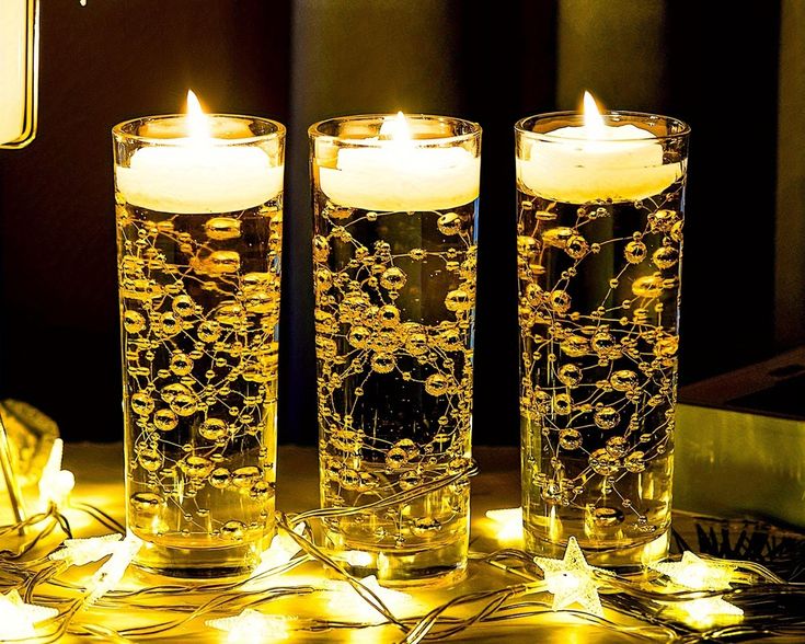 three lit candles sitting on top of a table next to each other in front of a mirror