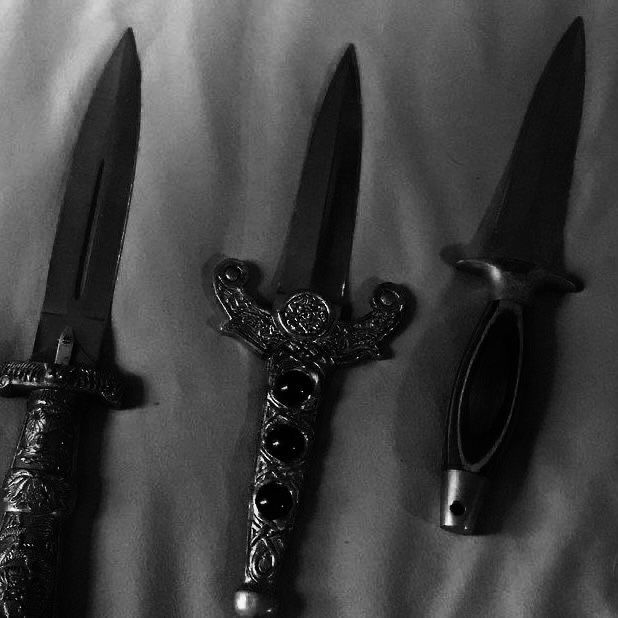 three different types of knifes on a white sheet with black stones in the center