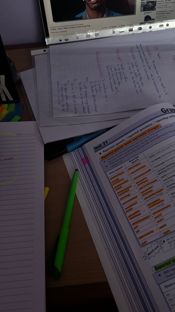 an open laptop computer sitting on top of a desk next to papers and pencils