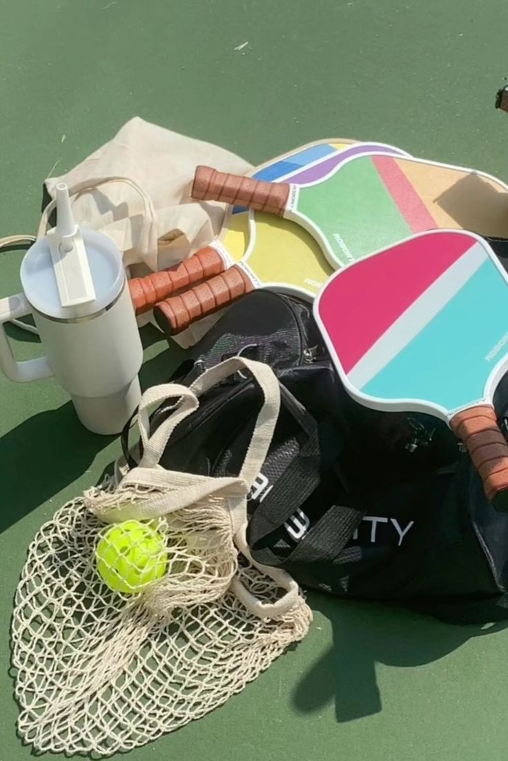 a tennis racquet, ball and bag on the court with other items around it