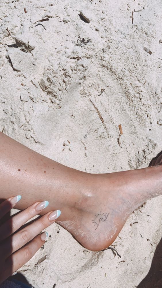 a woman's bare foot on the beach with her nails painted blue and white