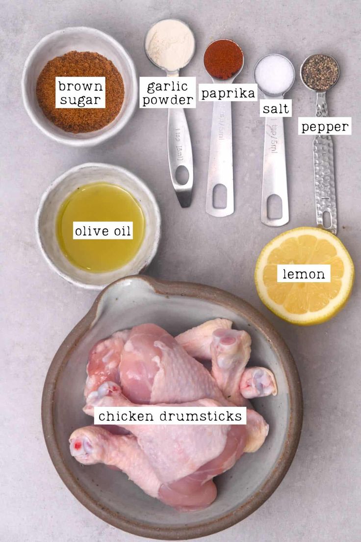 ingredients to make chicken broth laid out in bowls on a white surface with lemons, garlic and seasonings