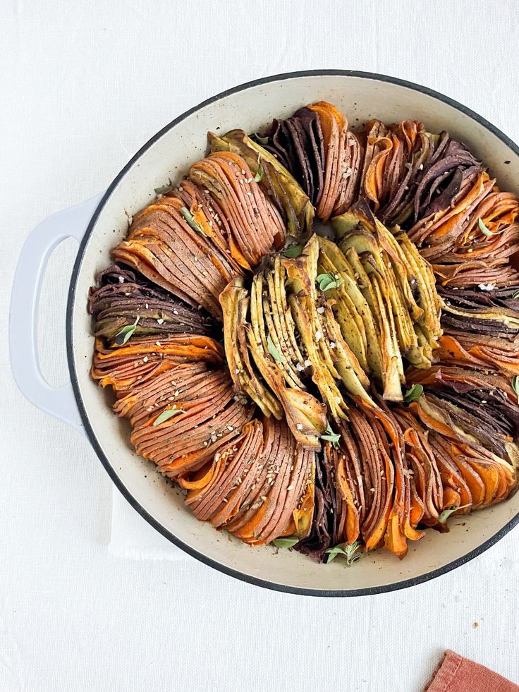 a pan filled with sliced up vegetables on top of a white tablecloth next to a napkin