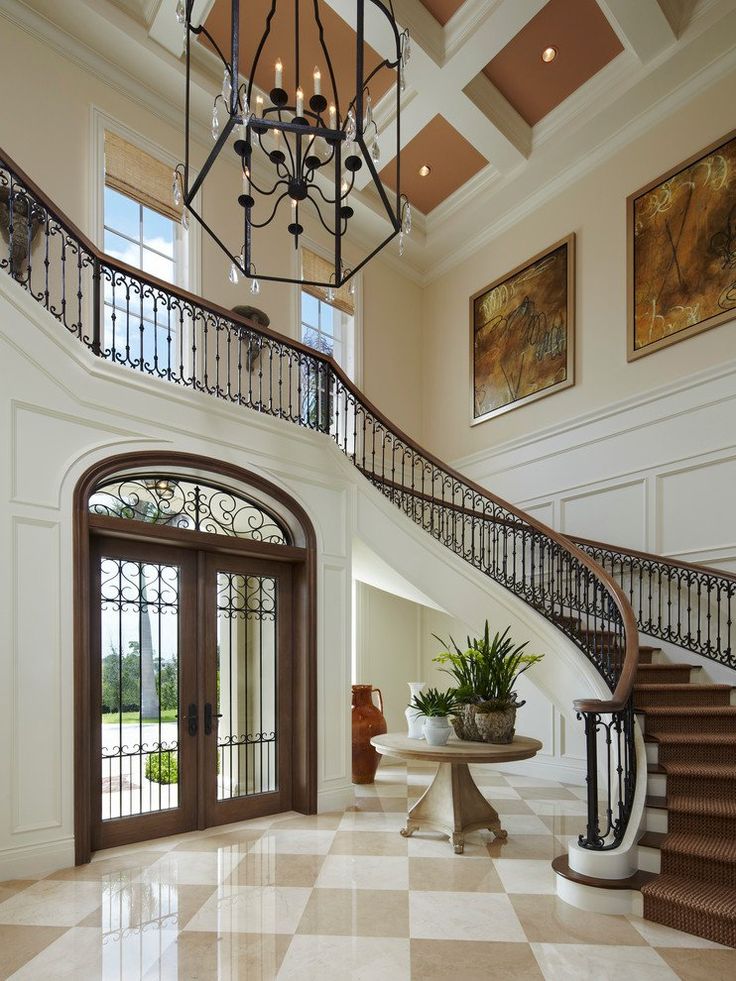 a foyer with marble flooring and wrought iron railings leading up to the second story