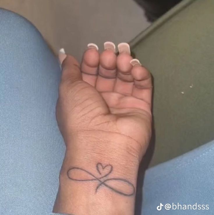 a woman's wrist with a small heart tattoo on her left hand and the word love written in cursive writing