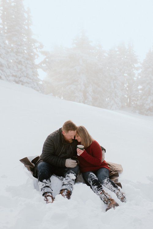 a man and woman sitting in the snow