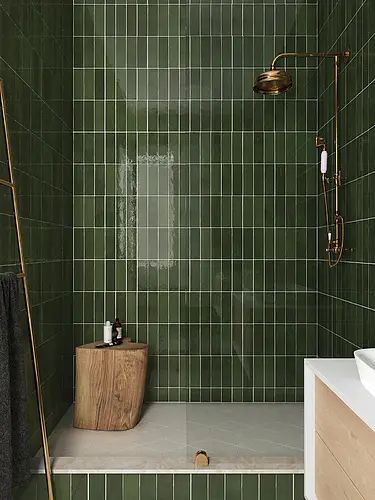 a green tiled bathroom with a wooden standup shower head and hand held faucet