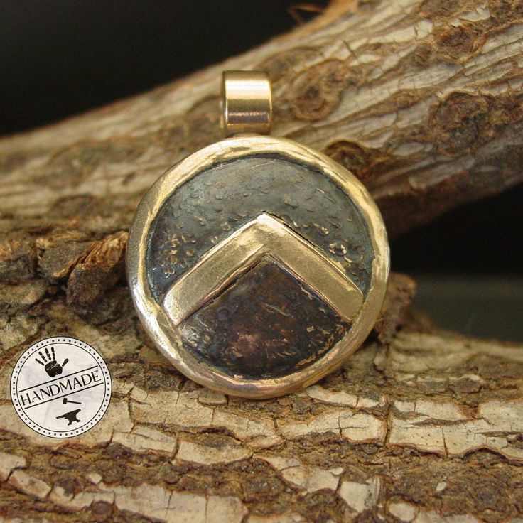 "This Spartan Shield necklace is hand sculpted, domed and beaten up to look like it has been on a battlefield. The letter lambda (Λ), standing for Laconia (administrative capital of Sparta) or Lacedaemon (ancient name for the city of Sparta), which was painted on the Spartans' shields, was first adopted in the 420s BC, and quickly became a widely known Spartan symbol. Military families passed on their shields to each generation as family heirlooms. - Hand sculpted pendant - Solid yellow bronze a Spiritual Bronze Hammered Necklace, Spiritual Hammered Bronze Necklace, Ancient Style Yellow Gold Brass Jewelry, Artisan Necklace With Round Pendant, Artisan Hand Cast Necklace With Round Pendant, Unique Hammered Round Pendant Necklace, Bronze Round Pendant Jewelry, Etched Copper Gold Jewelry, Etched Gold Copper Jewelry