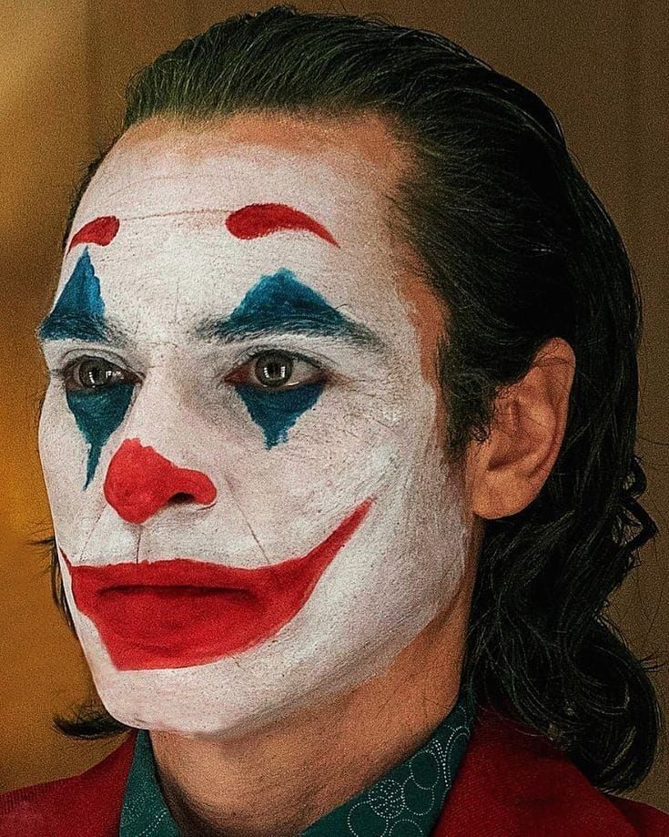 a close up of a person wearing a clown face paint on their face and hair