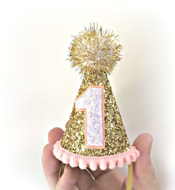 a hand holding a small birthday hat with the number one on it's side