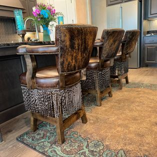 a group of brown chairs sitting on top of a rug in front of a kitchen