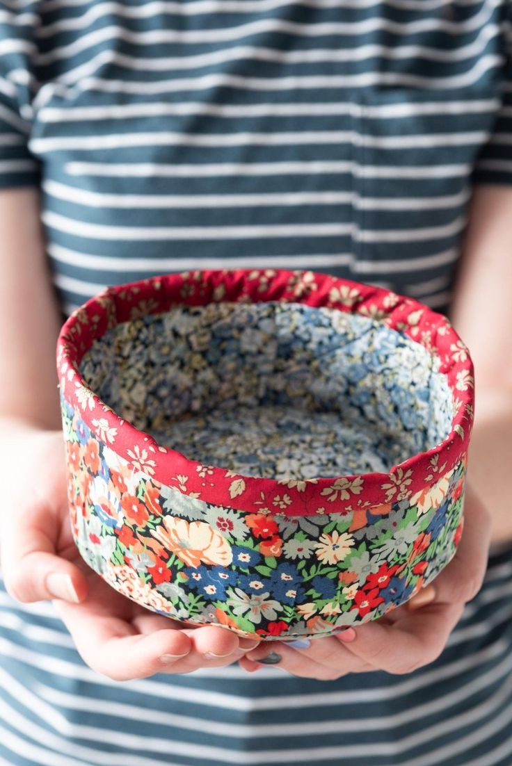 a person holding a bowl in their hands with floral designs on the bottom and sides