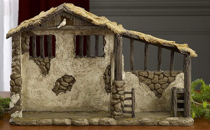 a statue of a house made out of rocks and wood with a bird perched on the roof