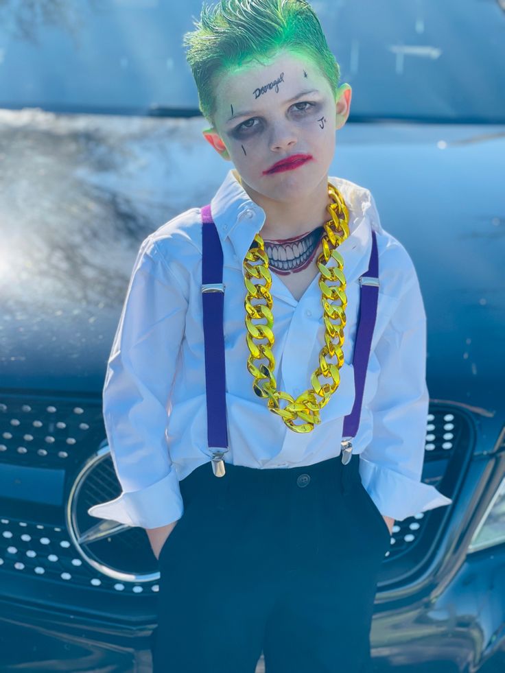 a young boy with green hair and clown make - up standing in front of a car