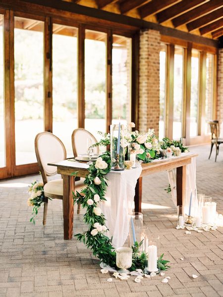 a long table with candles and flowers on it is set up for an outdoor wedding