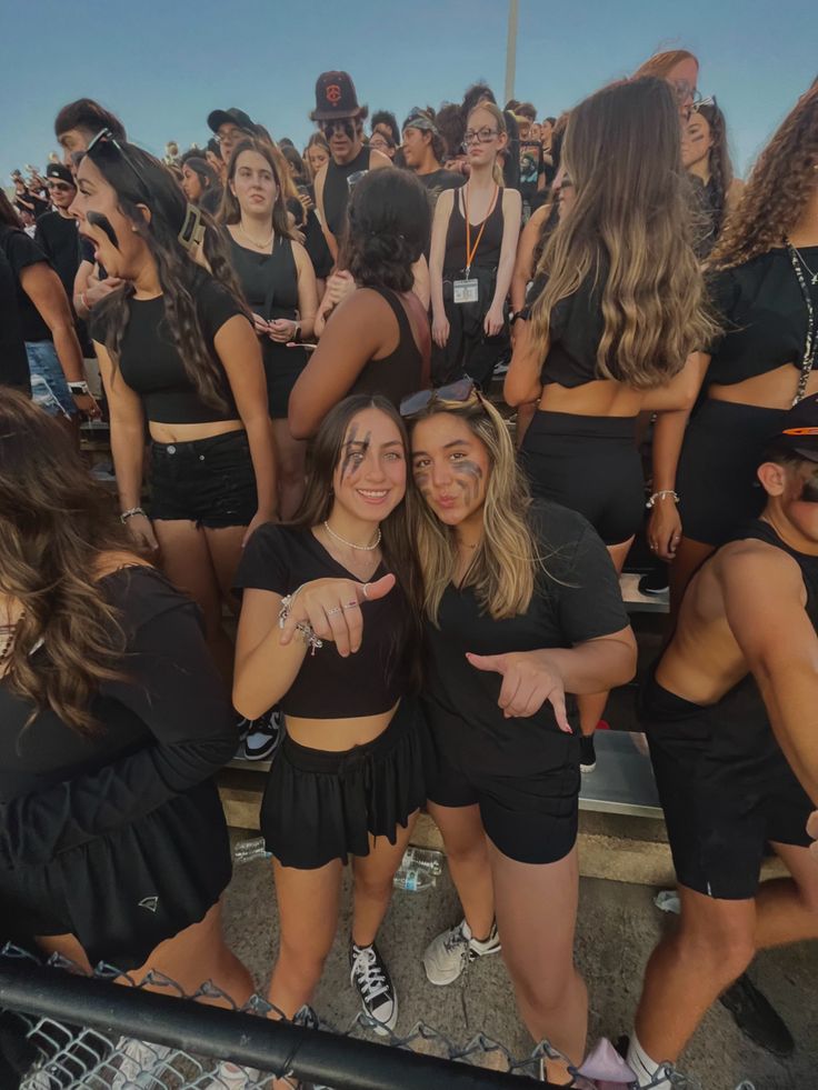 two girls posing for the camera in front of a crowd