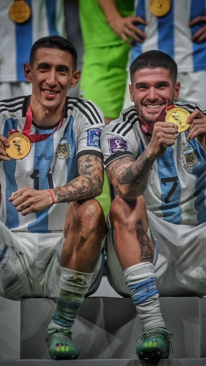 two soccer players sitting on a bench with medals in their hands and one holding the same medal