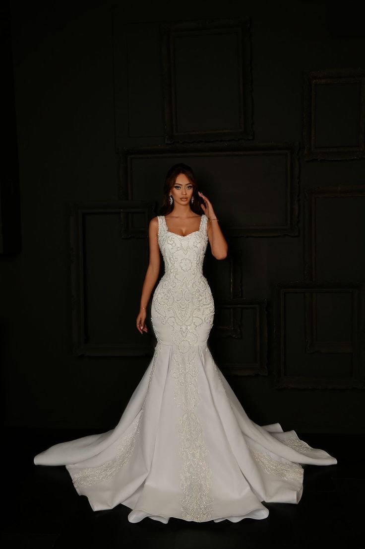 a woman in a white wedding dress posing for the camera with her hand on her head