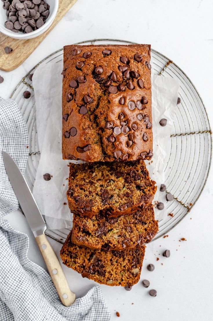 two slices of chocolate chip banana bread on a glass plate next to a bowl of chocolate chips