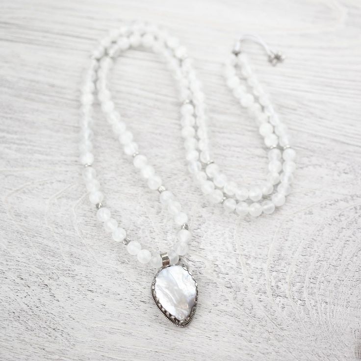 Less than 5 available. This limited edition DharmaShop exclusive mala features 108 high-quality Selenite beads from Morocco along with a handcrafted Mother of Pearl pendant from Nepal. Selenite is incredibly special with an energy like no other. Wearing this mala can help to cleanse negativity energy and bring clarity, relaxation and tranquility. A gorgeous piece of Mother of Pearl sits inside of an intricately hand carved silver-plated brass setting to create a stunning one-of-a-kind centerpiec White Adjustable Mala With Gemstone Beads, Adjustable White Gemstone Beads Mala, Adjustable White Mala With Gemstone Beads, White Gemstone Beads Mala For Healing, Handmade White Mala For Healing, Clear Negative Energy, Adjustable Knot, Energy Bracelets, Power Crystals