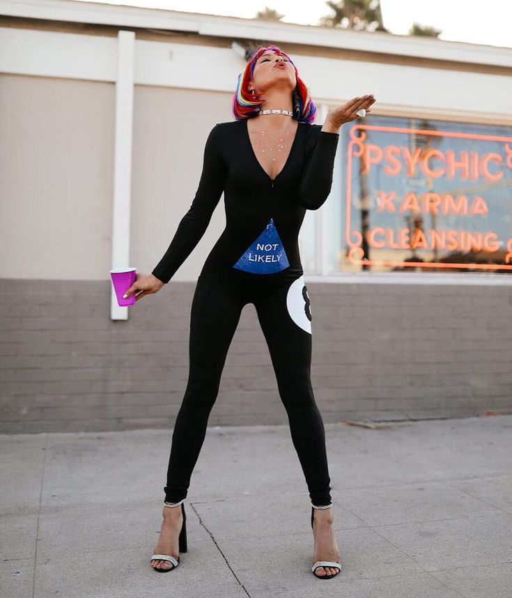 a woman in a black bodysuit is standing on the sidewalk with her eyes closed