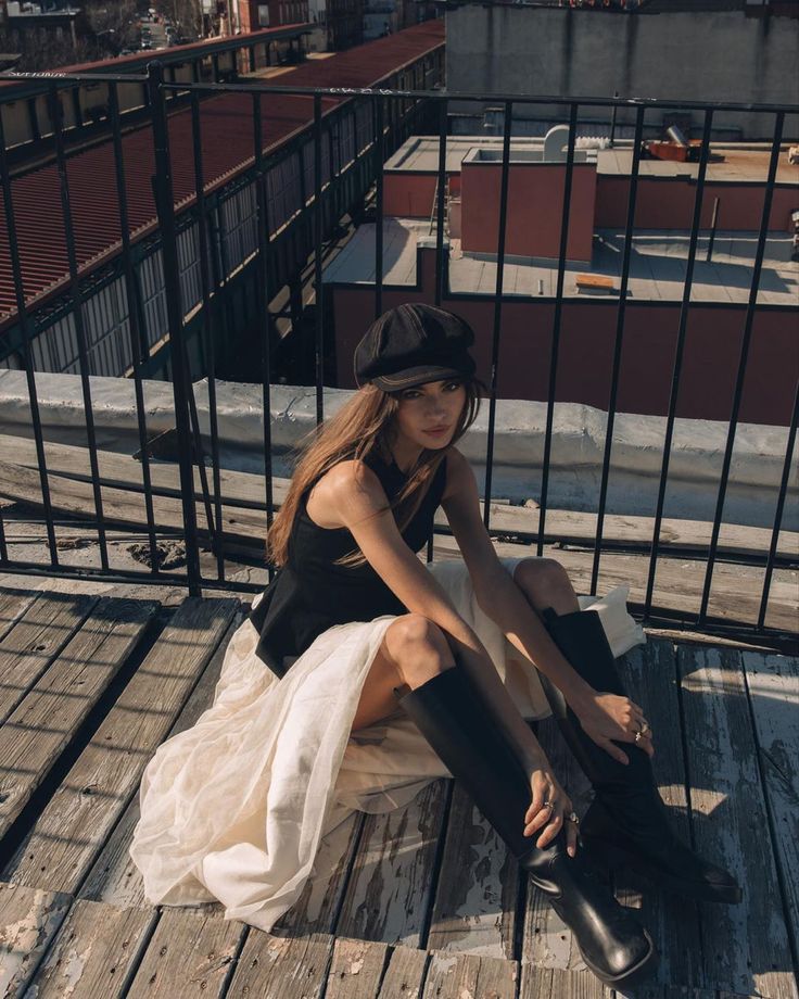 a woman sitting on top of a wooden floor next to a black metal fence and building