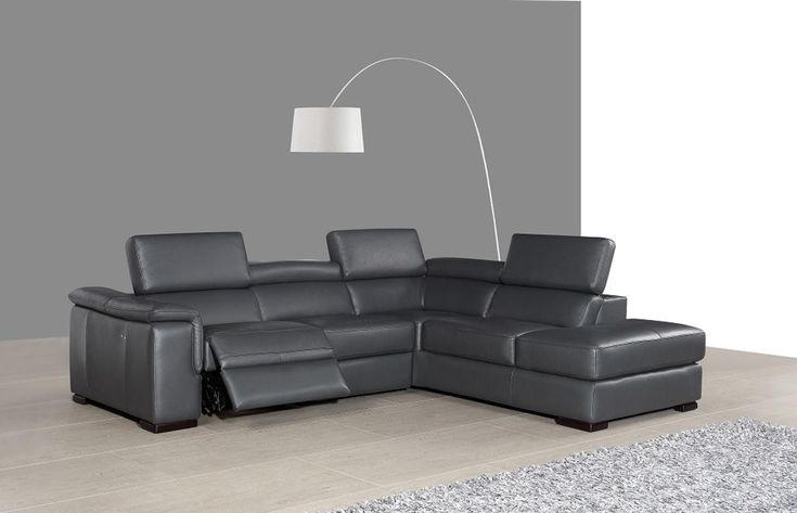 a grey leather sectional sofa with recliners and a lamp on the wall behind it