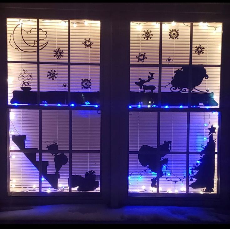 the window is decorated with christmas lights and silhouettes of people in sleighs