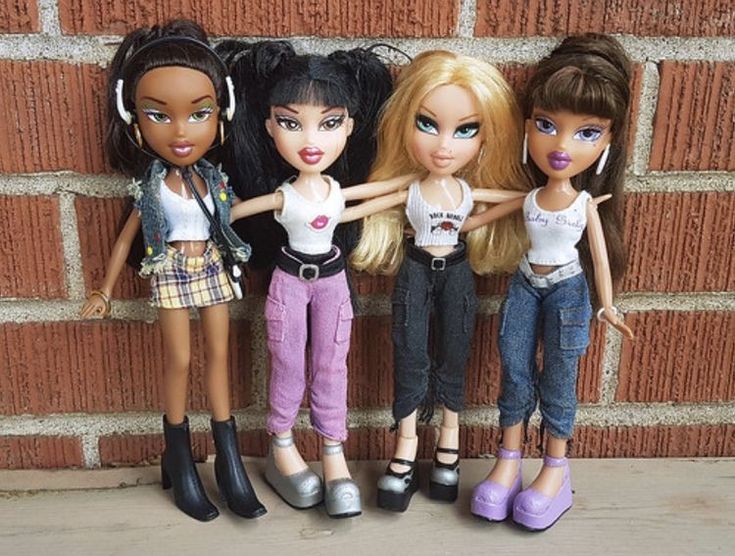 five dolls are lined up against a brick wall, one is wearing headphones and the other has her hands on her hips