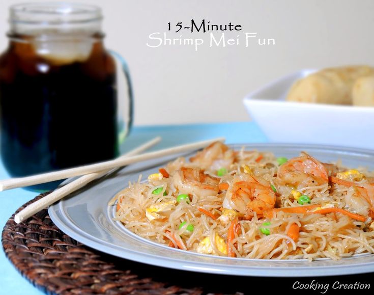 a white plate topped with noodles and shrimp next to a jar of jelly sauce on a blue table