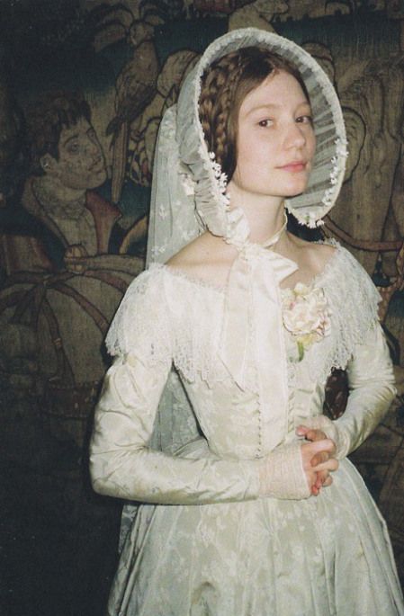 a woman wearing a white dress and bonnet