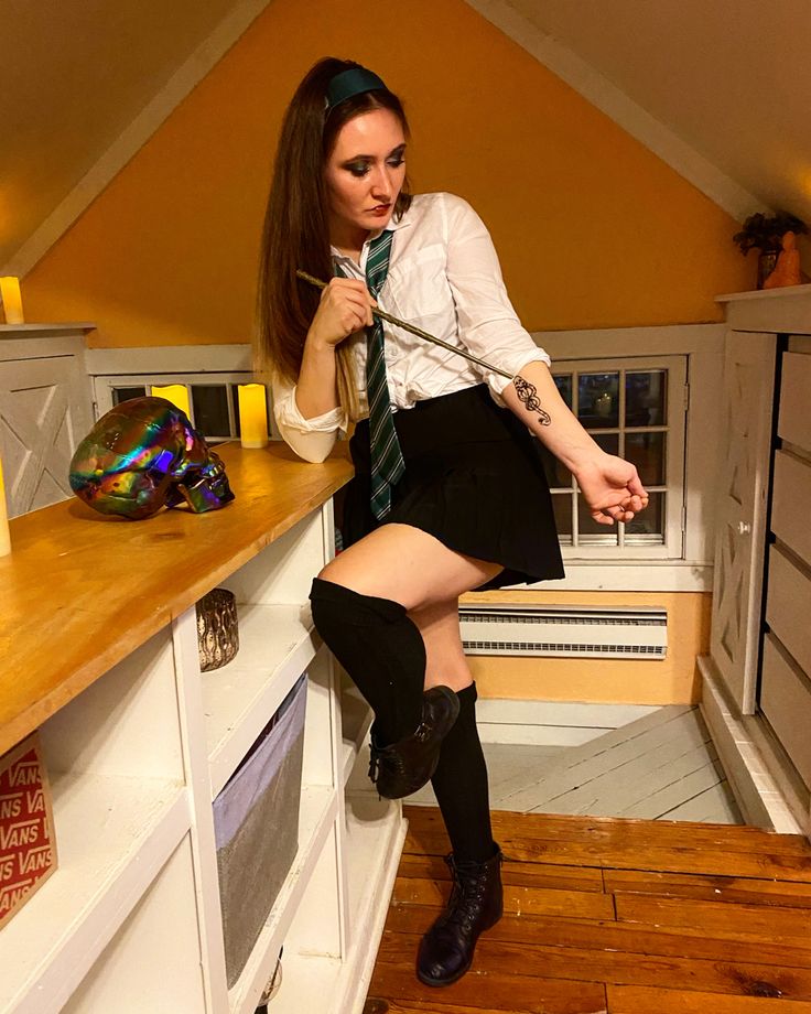 a woman in a skirt and tie sitting on a counter