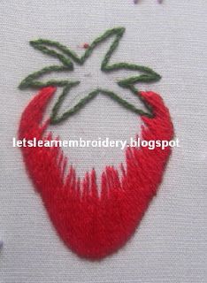 a close up of a red strawberry embroidered on a white cloth