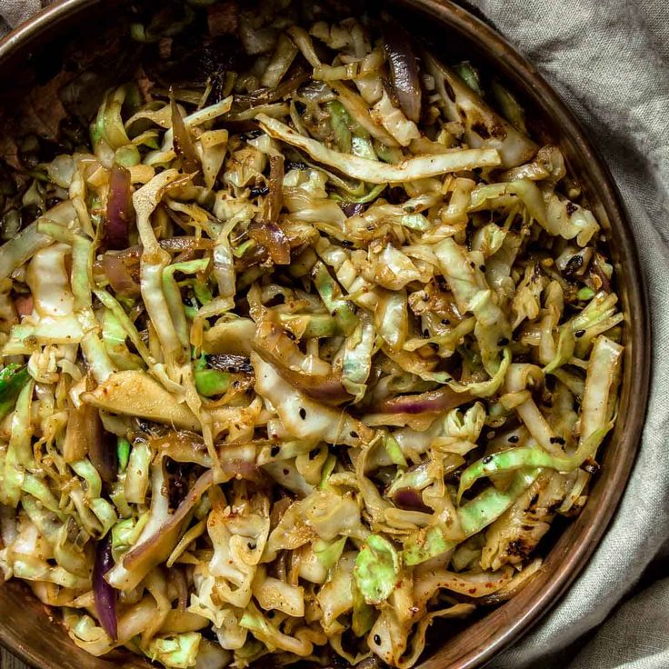 a bowl filled with coleslaw and onions on top of a cloth covered table