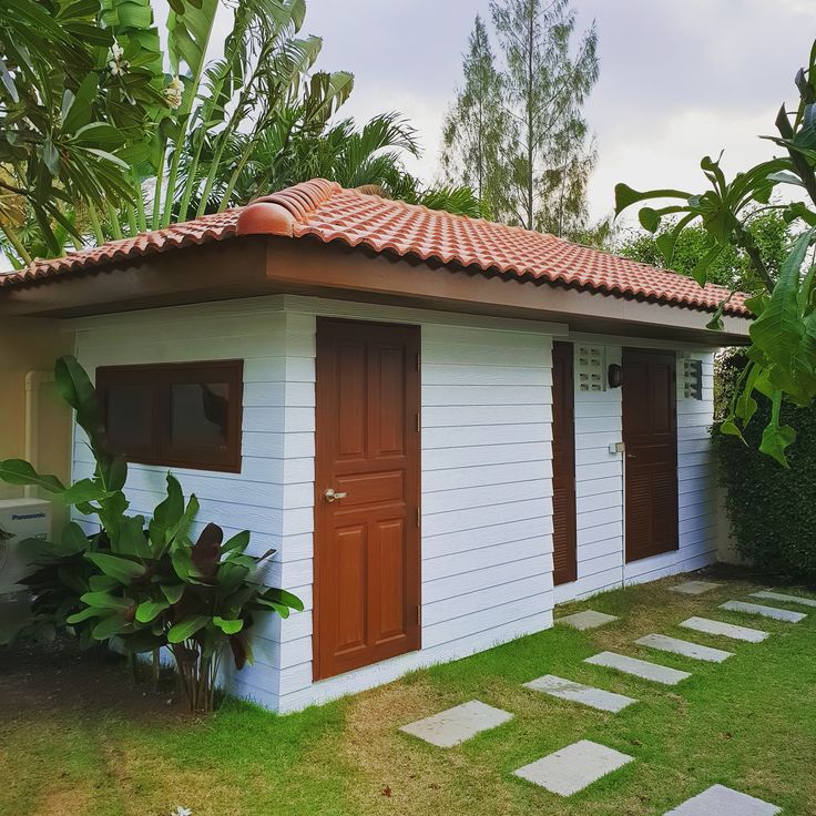 a small white building with a red roof and two doors on the side of it