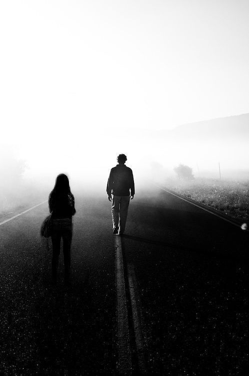 two people walking down the road in the fog